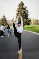 Woman in sport outfit on the road doing doing splits standing. photo