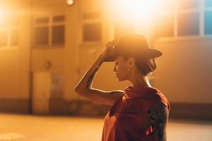 The young, attractive girl in a hat poses to the camera at night photo