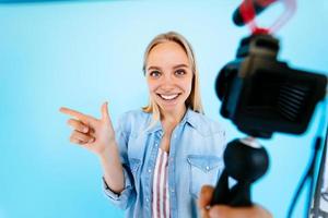 hermosa chica blogger hace sus necesidades en la cámara aislado fondo azul foto