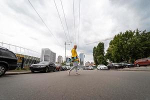 una hermosa joven sostiene una patineta y cruza la calle foto