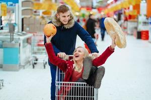 Young handsome guy rides a girl in a supermarket in a trolley photo