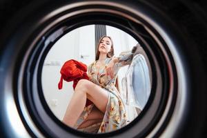 Young woman at home puts the dress in the drying machine. photo