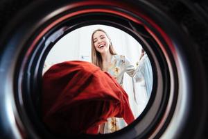 mujer joven en casa pone el vestido en la secadora. foto