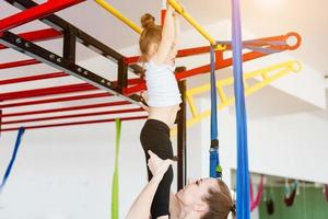 Little girl hanging on the crossbar, mom supports photo