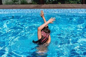Beautiful teenage girl relaxing in pool water photo