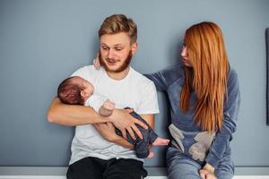 familia joven con un bebé junto a la pared foto