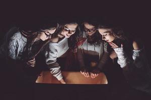 Sisters opens a box with a Christmas present and fascinated looks inside photo