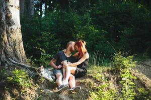 hermosa pareja sentada en un bosque cerca del árbol foto