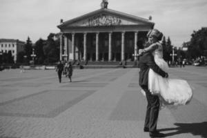 groom holds bride in his arms and twisted photo