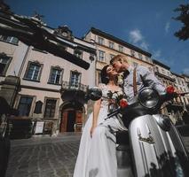 bride and groom on vintage motor scooter photo