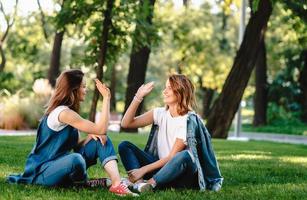 Felices amigas levantando la mano dando cinco en el parque de la ciudad foto