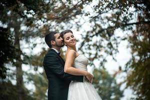 groom embracing bride from back photo