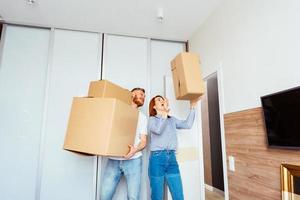 Happy couple holding cardboard boxes and moving to new place photo