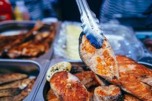 Cooked salmon steak baked on the grill in kitchen tong. photo