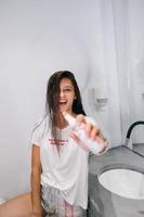 Young woman holds in hand to point shows to camera, care product bottle photo