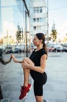 Young beautiful girl doing stretching in front of a modern building photo