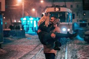 pareja de adultos jóvenes en la línea de tranvía cubierta de nieve foto