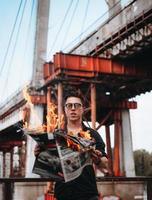 Guy reads a burning newspaper, in the background a bridge photo