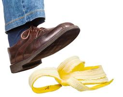 pie derecho en jeans y zapatos resbalones en cáscara de plátano foto