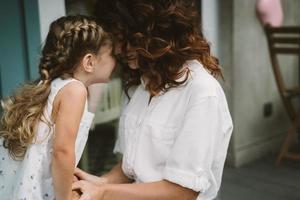 retrato de una pequeña hija besando a su hermosa y feliz madre foto