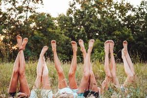 Six girls lie on the grass and raise their legs up photo