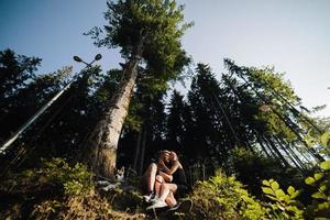 beautiful couple sitting in a forest near the tree photo