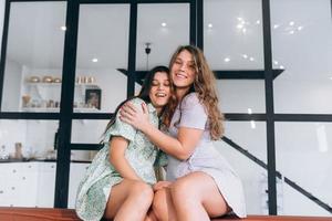 chicas felices abrazándose en casa sentadas en un sofá en la sala de estar foto