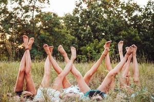 Six girls lie on the grass and raise their legs up photo