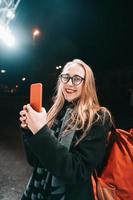 mujer rubia con smartphone por la noche en la calle. foto