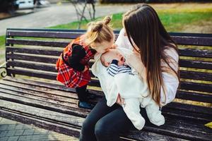 mother and two daughters rest on a bench photo