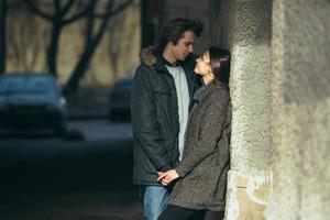 young couple standing together in front of wall photo