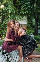 two girls in the park hugging on the bench photo