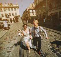 the bride and groom running along streets photo