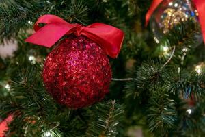 adorno navideño de lentejuelas rojas en un árbol. tarjeta de felicitación festiva para la celebración de invierno. foto