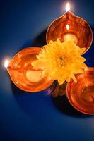 Happy Diwali. Celebrating the Hindu Light Festival. Traditional diya oil lamps and flowers on blue background. photo