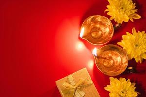 Happy Diwali. Diya oil lamp, flowers and gift boxes on red background. Celebrating the Indian traditional festival of light. photo