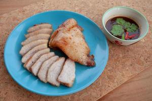 cerdo asado y salsa picante tailandesa en la mesa de madera. comida callejera de tailandia. foto