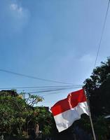 la bandera indonesia es roja y blanca con un fondo de cielo azul brillante foto