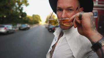 homme avec des tatouages et des lunettes de soleil regardant la caméra video