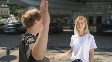 Teenager-Jungen und -Mädchen mit Rucksäcken und Skateboard stehen und unterhalten sich im sonnigen Stadtraum im Freien video