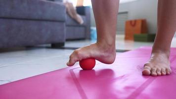 Woman exercising with rubber ball on pink mat in living room video