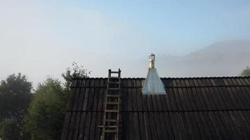 Rising over a wooden roof to reveal  bright foggy day in Carpathian Mountains in Ukraine video