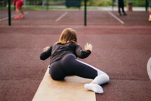 Young fit woman in sportswear trains outdoors on the playground. photo