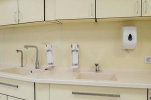 elbow soap and antiseptic dispenser or sanitizer wall mounted for hand disinfection and water tap sink with faucet bathroom or clinic photo