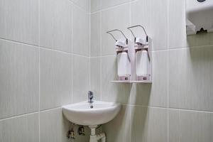 Codo dispensador de jabón y antiséptico o desinfectante montado en la pared para desinfección de manos y grifo de agua con grifo baño o clínica foto