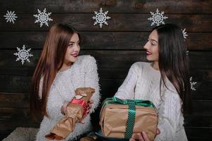 Two beautiful girls offer gifts to camera photo
