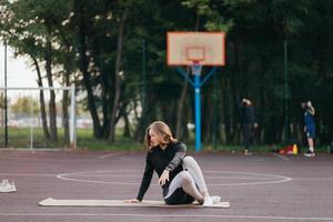 Young fit woman in sportswear trains outdoors on the playground. photo