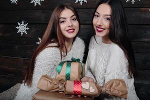 Two beautiful girls offer gifts to camera photo