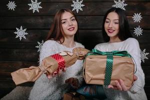 dos hermosas chicas ofrecen regalos a la cámara foto