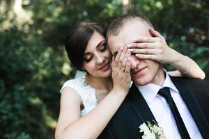 Charming bride closes eyes to her husband from behind photo